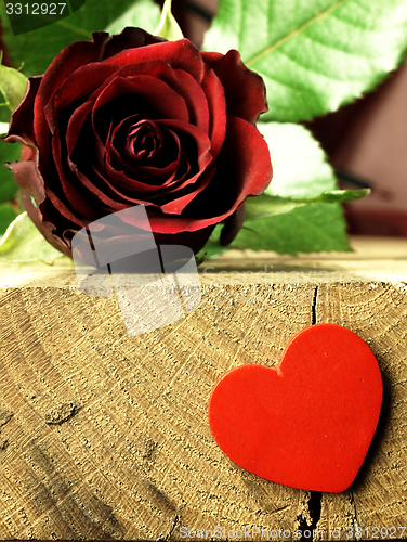 Image of Red rose and red heart on a wooden table.
