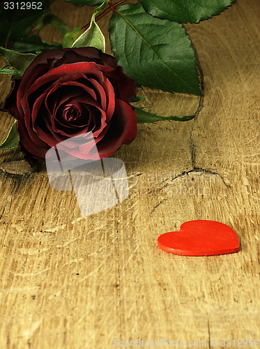 Image of Red rose and red heart on a wooden table.