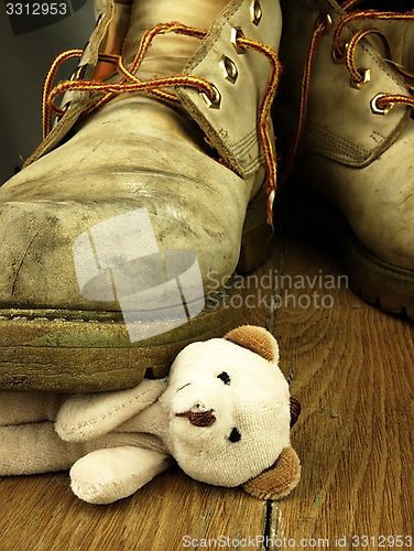 Image of Teddy bear crushed by a heavy, old military boot.