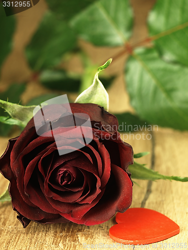 Image of Red rose and red heart on a wooden table.