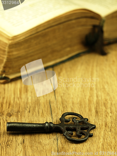 Image of Key and old, open book with a damaged cover.