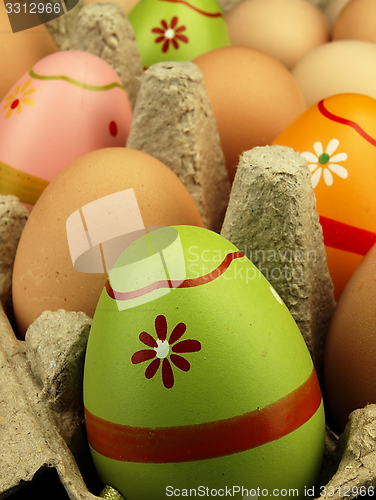 Image of Colorful Easter eggs in the company of ordinary eggs.