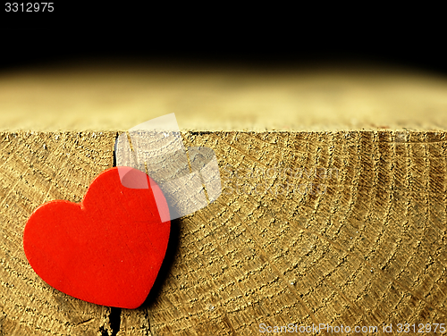 Image of Red heart on the edge of a wooden table.