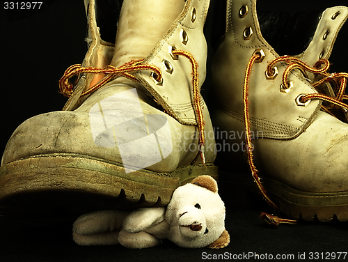 Image of Teddy bear crushed by a heavy, old military boot.