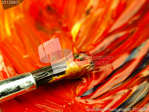 Image of Colored paint mixed on palette. Dirty brush in the foreground.