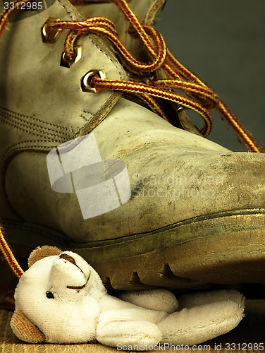 Image of Teddy bear crushed by a heavy, old military boot.