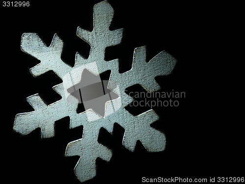 Image of Huge white wooden snowflake and black background.