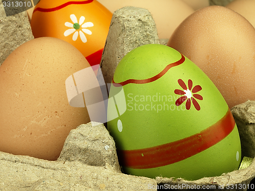 Image of Colorful Easter eggs in the company of ordinary eggs.