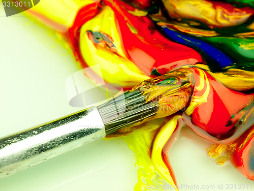 Image of Colored paint mixed on palette. Dirty brush in the foreground.