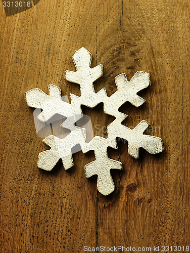 Image of Huge white snowflake and wooden background.