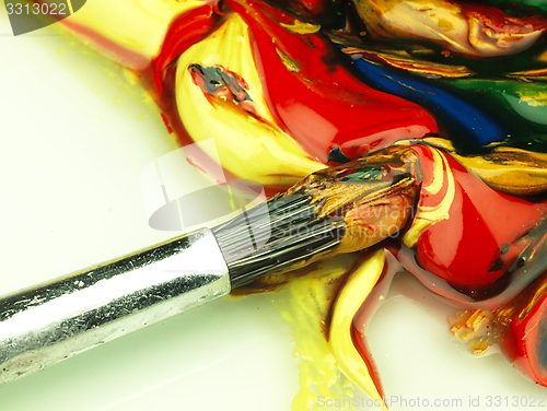 Image of Colored paint mixed on palette. Dirty brush in the foreground.