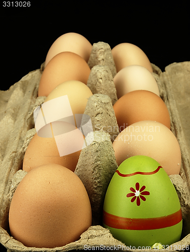 Image of Colorful Easter egg in the company of ordinary eggs.