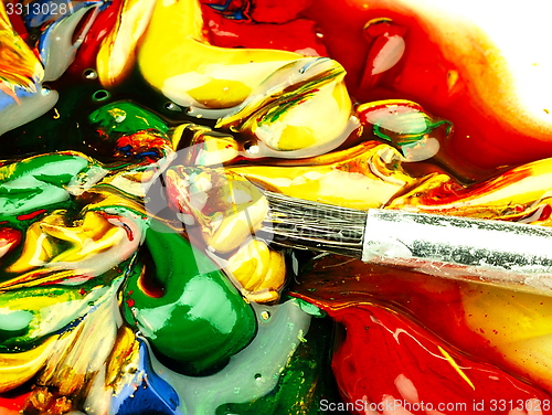 Image of Colored paint mixed on palette. Dirty brush in the foreground.