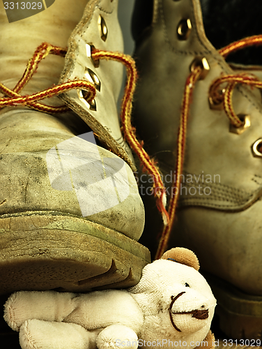 Image of Teddy bear crushed by a heavy, old military boot.