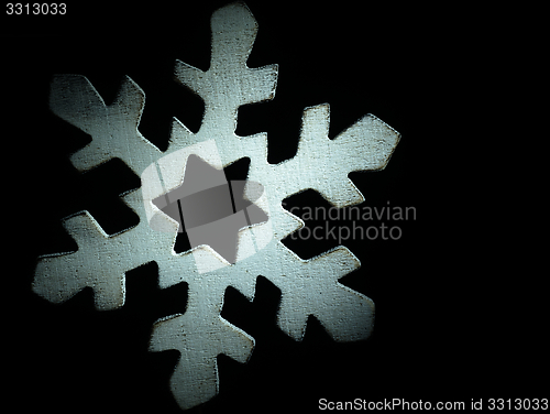 Image of Huge white wooden snowflake and black background.