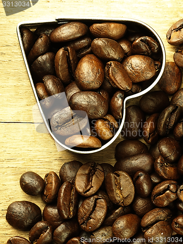 Image of Heart and Coffee beans close-up on wooden, oak table.