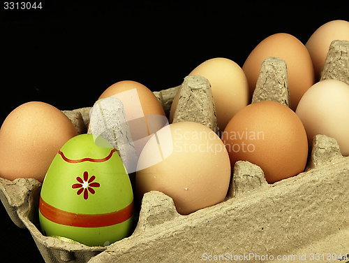 Image of Colorful Easter egg in the company of ordinary eggs.