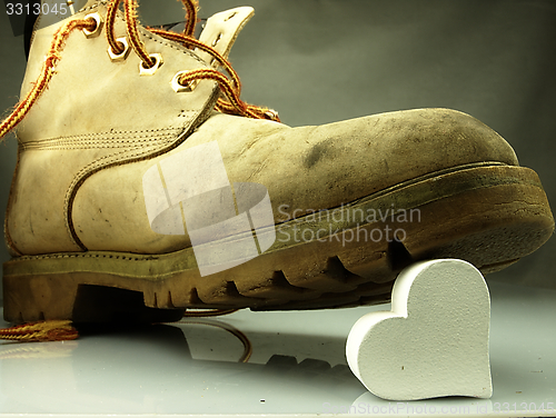 Image of Heavy military boot trampling heart.