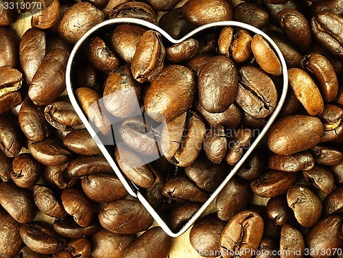 Image of Heart and Coffee beans close-up on wooden, oak table.