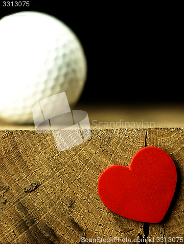 Image of Golf ball and heart on the edge of table.