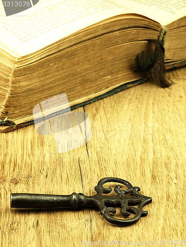 Image of Key and old, open book with a damaged cover.