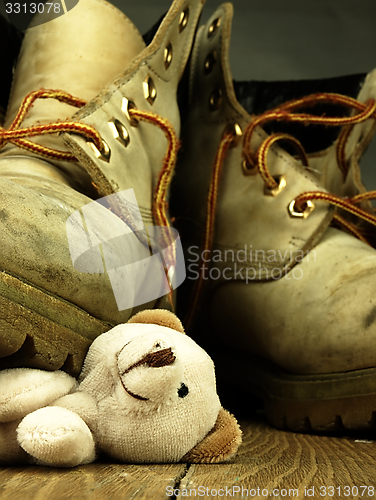 Image of Teddy bear crushed by a heavy, old military boot.