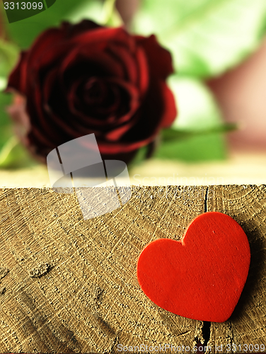 Image of Red rose and red heart on a wooden table.