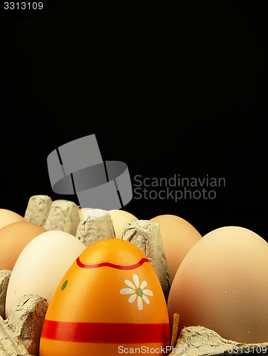 Image of Colorful Easter egg in the company of ordinary eggs.