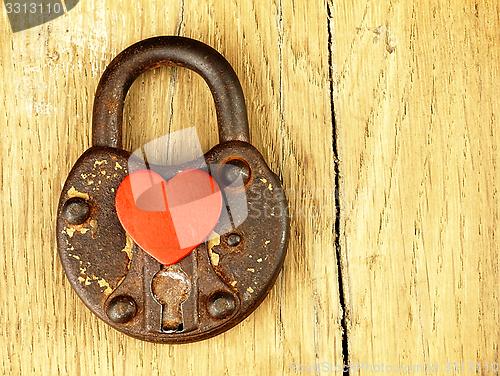 Image of Rusty padlock and heart on a wooden background.