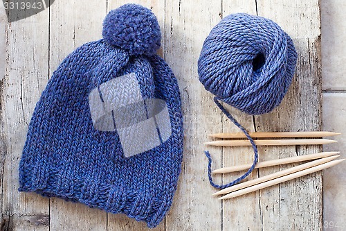 Image of wool blue hat, knitting needles and yarn