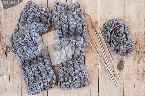 Image of wool grey legwarmers, knitting needles and yarn