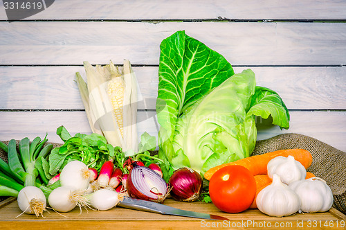 Image of Vegetables on a wooden table with a knife