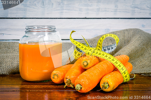 Image of Carrots with measure tape and juice on a table