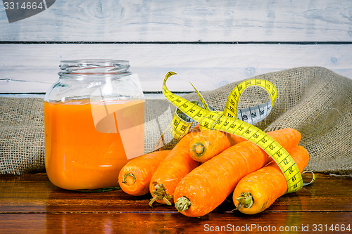 Image of Carrots with measure tape and juice on a table