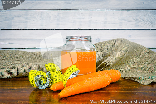 Image of Carrot juice with measure tape on a table