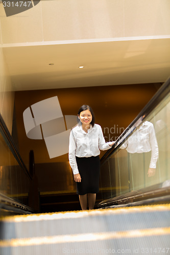 Image of Young Asian female executive going up escalator