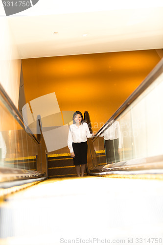 Image of Young Asian female executive going up escalator