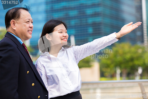 Image of Senior businessman and young female executive pointing at a direction