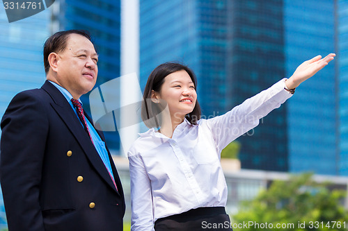 Image of Senior businessman and young female executive pointing at a direction