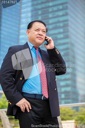 Image of Senior businessman in suit using smart phone