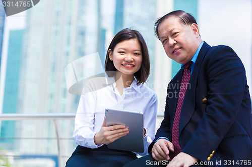 Image of Senior businessman and young female executive using tablet PC