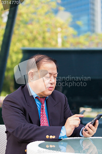 Image of Senior businessman in suit using smart phone