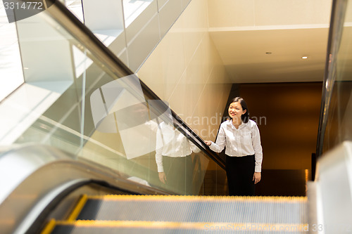 Image of Young Asian female executive going up escalator