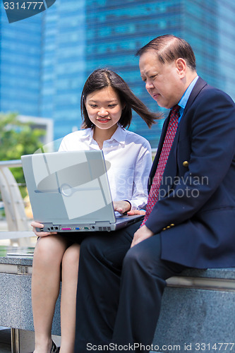 Image of no Young Asian female executive and senior businessman using laptop PC