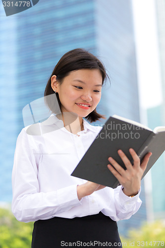 Image of Young Asian female executive reading book smiling portrait