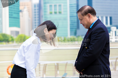 Image of Young Asian female executive and senior businessman in suit bowing to each other