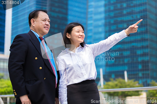 Image of Senior businessman and young female executive pointing at a direction