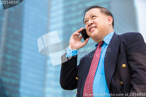 Image of Senior businessman in suit using smart phone