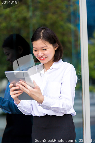 Image of Young Asian female executive using tablet PC