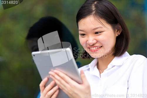 Image of Young Asian female executive using tablet PC